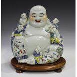 A Chinese famille rose enamelled porcelain figure of a seated Buddha, 20th century, with five boy