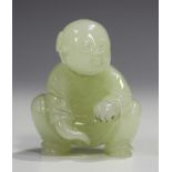 A Chinese pale celadon jade carving of a boy, probably 20th century, modelled crouching with smiling