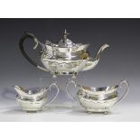A George V silver three-piece tea set of oval form with banded and faceted decoration, comprising