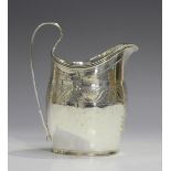 A George III silver cream jug of oval form with reeded rim and loop handle, the body engraved with a