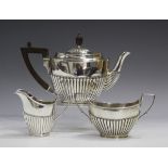 A late Victorian silver bachelor's three-piece tea set of oval form with half-reeded decoration,