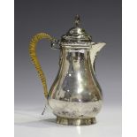 An Edwardian silver hot water pot of baluster form, the hinged lid with spiral fluted finial, London