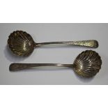 A near pair of George III silver sauce ladles, each with scalloped bowl and later engraved