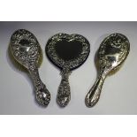 A late Victorian silver heart shaped dressing table hand mirror, pierced and embossed with scrolling