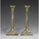 A pair of late Victorian silver Corinthian column candlesticks, each with detachable nozzle, on a
