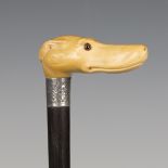 A late Victorian ebony walking cane, the ivory handle carved as a dog's head with inset glass eyes