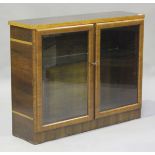 A French Art Deco walnut dwarf bookcase, fitted with a pair of glazed doors, height 89cm, width