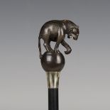 An early 20th century ebonized walking cane, the horn handle carved as a tiger above a nickel plated