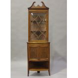 An Edwardian satinwood corner display cabinet, inlaid with urns and swags, the swan neck pediment