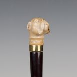 A late 19th century ebonized walking cane, the handle carved as a dog's head above a gilt metal