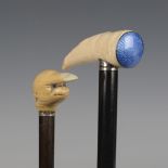 An early 20th century ebonized walking cane, the carved ivory handle with a blue enamelled plaque,