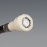 A late 19th century ebonized walking cane, the ivory screw-off handle top inset with a glazed