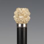 A late 19th century ebonized walking cane, the Japanese ivory handle carved with overall faces above