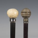 An Edwardian ebonized walking cane, the ivory handle carved in relief with flowers above a silver