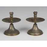 A pair of late 19th century gilt and silvered brass candlesticks, the wide drip pans and circular