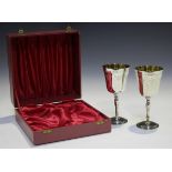 A pair of Elizabeth II silver goblets, each gilt-lined tapered bowl engraved with floral garlands,
