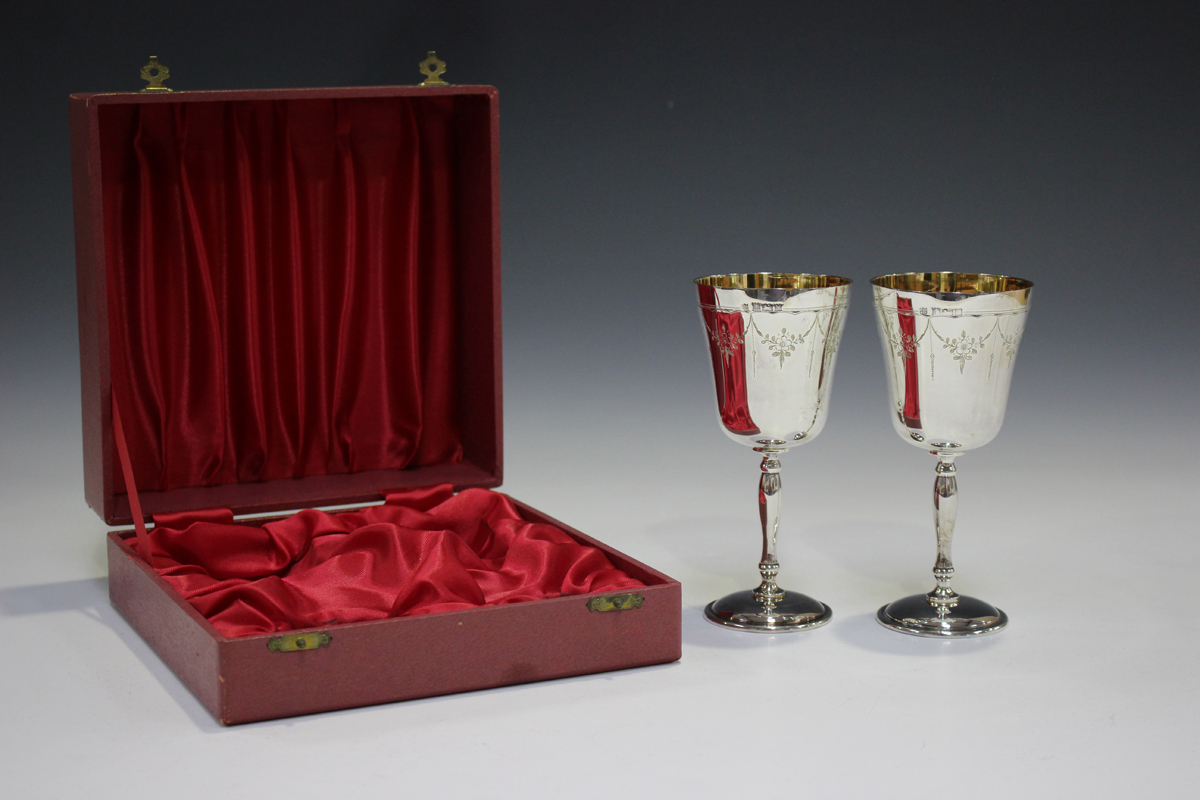 A pair of Elizabeth II silver goblets, each gilt-lined tapered bowl engraved with floral garlands,