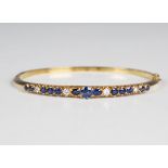 An 18ct gold, sapphire and diamond oval hinged bangle, mounted with a row of graduated circular