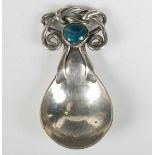 An Arts and Crafts silver caddy spoon, the hammered bowl with intertwined scroll handle, set with