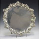 An Edwardian silver salver with raised scroll and scallop shell rim, on claw and ball feet,