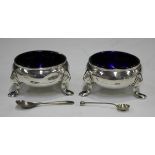 A pair of George II silver circular salts, fitted with blue glass liners, on scroll legs and hoof