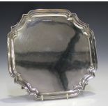 A George VI silver salver of shaped square form with piecrust rim, on four foliate capped scroll