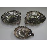 A pair of George V silver butter shells with cast scallop shell moulded handles, on ball feet,