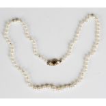 A single row necklace of graduated cultured pearls on a gold, garnet and cultured pearl clasp, total