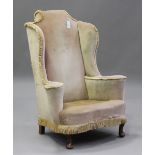 An early 20th century Queen Anne style walnut framed wingback armchair, upholstered in fringed