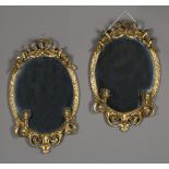 A pair of late Victorian gilt painted composition oval girandole wall mirrors with floral swag and