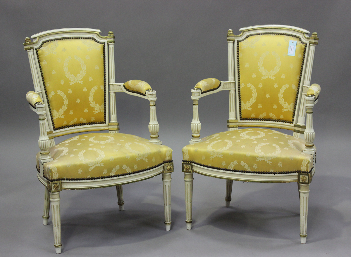 A pair of 20th century Louis XVI style white painted and gilt fauteuil armchairs, upholstered in