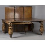 A large late Victorian carved oak extending dining table, the top fitted with four extra leaves, the