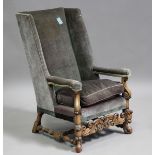 An early 20th century Carolean Revival walnut framed armchair, upholstered in blue velour, on carved