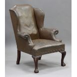 An early/mid-20th century George III style brown leather wing back armchair with studded scroll