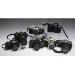 A collection of 35mm cameras and lenses, including a Canon A-1 with 50mm lens, a Pentax P30T with