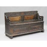 An 18th century provincial oak hall settle with carved decoration, the box seat flanked by pierced
