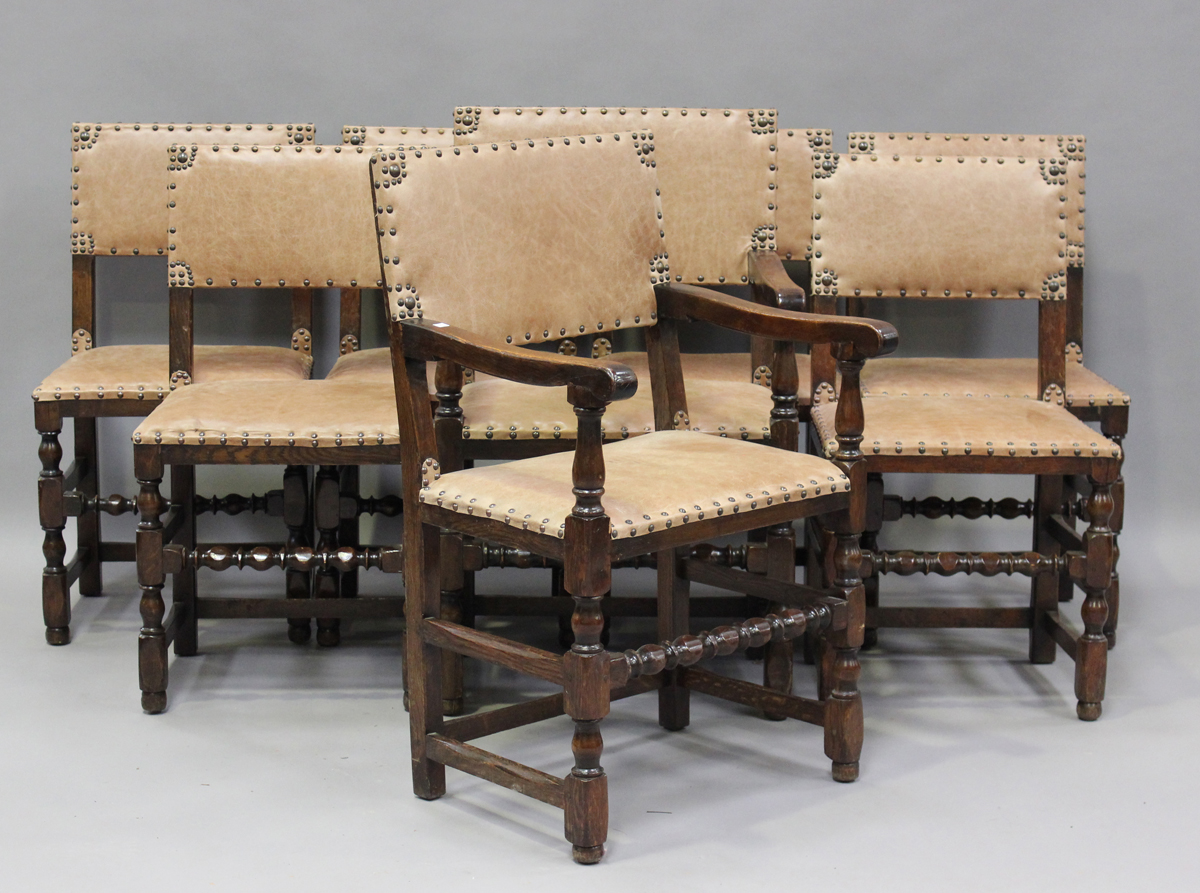 A set of eight Jacobean Revival oak dining chairs with light brown leather seats and backs,