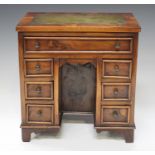 A 20th century reproduction yew diminutive model of a kneehole desk, the top inset with green