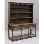 An early 20th century oak dresser, fitted with a plate rack above three drawers and a pot shelf,