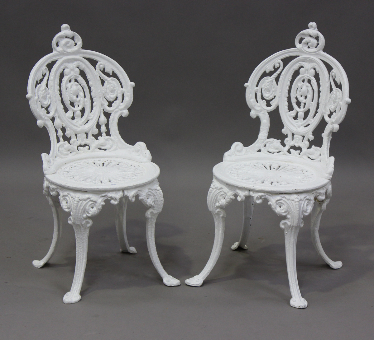 A pair of late Victorian white painted cast iron garden chairs of foliate scroll form, height