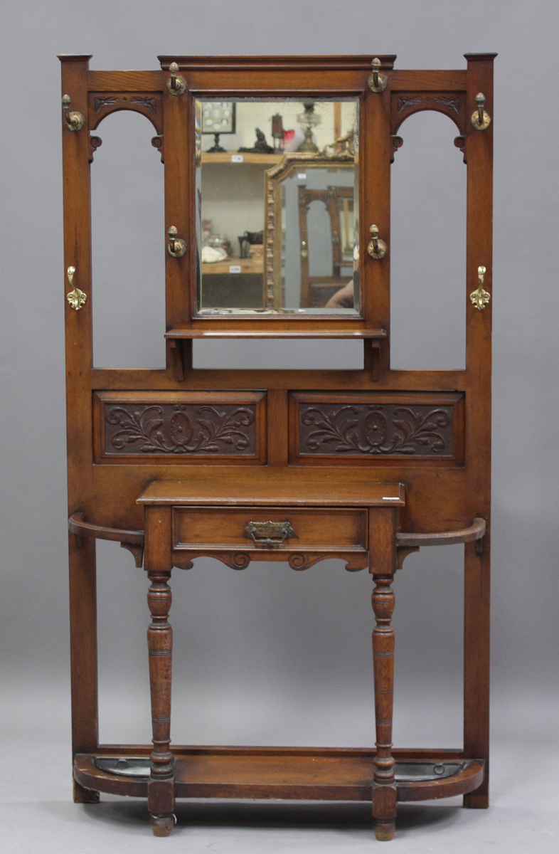 A late Victorian oak hallstand with carved foliate decoration, fitted with a drawer, on turned