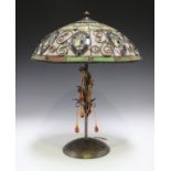 A modern bronzed metal table lamp with a Tiffany style stained glass shade, the foliate stem hung