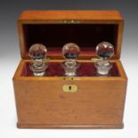 A late Victorian oak three-bottle decanter box, enclosing three cut glass decanters and stoppers,