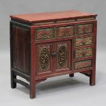 A 19th century Chinese red painted softwood side cabinet, the carved and pierced doors and drawers