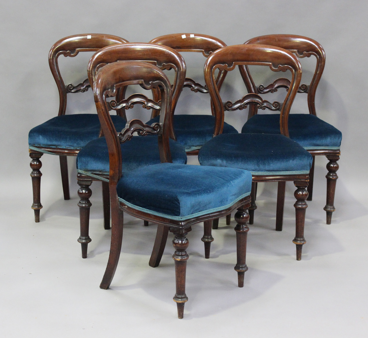 A set of six Victorian mahogany balloon back dining chairs, the overstuffed seats on turned legs,