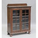 A George V oak glazed bookcase, the two doors inset with bevelled glass panels, height 120cm,