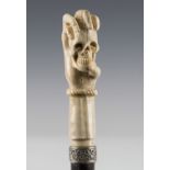 A late 19th/early 20th century ebonized walking cane, the carved antler handle modelled as a hand