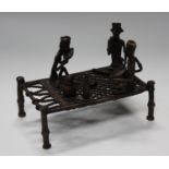 An Indian patinated bronze figure group of three seated men, eating at a table, length 15cm.Buyer’