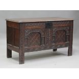 A late 17th century panelled oak coffer, the hinged lid above a frieze carved with foliate