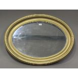 An early 20th century later gilt painted oval wall mirror with bevelled plate glass, 95cm x 70cm.
